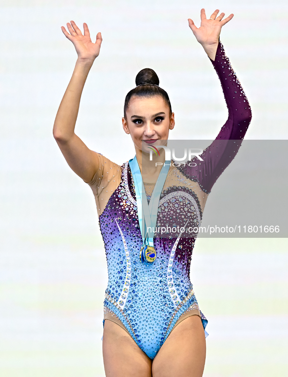 Gold medalist Alina Harnasko of Belarus celebrates on the podium after the Individual Clubs Final of the International Rhythmic Gymnastics T...