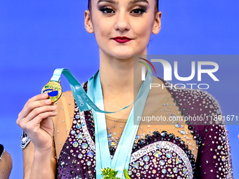 Gold medalist Alina Harnasko of Belarus celebrates on the podium after the Individual Clubs Final of the International Rhythmic Gymnastics T...