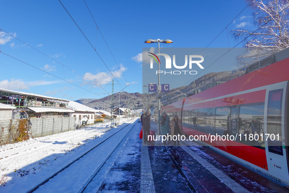 A red Deutsche Bahn train at Kochel am See Station in Bavaria, Germany, on November 22, 2024, contrasts with the pristine white snow coverin...