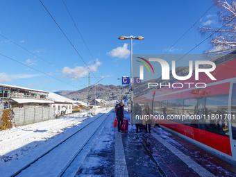 A red Deutsche Bahn train at Kochel am See Station in Bavaria, Germany, on November 22, 2024, contrasts with the pristine white snow coverin...