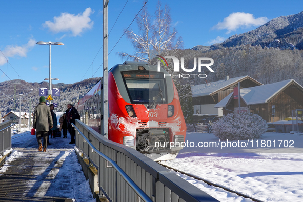 A red Deutsche Bahn train at Kochel am See Station in Bavaria, Germany, on November 22, 2024, contrasts with the pristine white snow coverin...