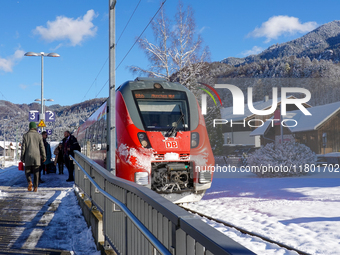 A red Deutsche Bahn train at Kochel am See Station in Bavaria, Germany, on November 22, 2024, contrasts with the pristine white snow coverin...