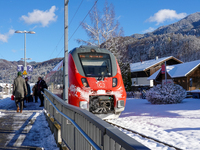 A red Deutsche Bahn train at Kochel am See Station in Bavaria, Germany, on November 22, 2024, contrasts with the pristine white snow coverin...