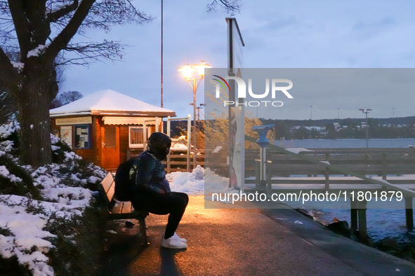 This photograph showcases the wintery calm of the lakeside promenade at Lake Starnberg in Bavaria, Germany, on November 22, 2024. A solitary...