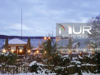 A view of the waterfront promenade at Lake Starnberg on November 22, 2024. Snow covers the ticket booth of the Bayerische Seenschifffahrt Gm...