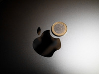 An Apple logo is on the back of a MacBook next to a one Euro coin in Athens, Greece, on November 23, 2024. (