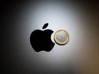 An Apple logo is on the back of a MacBook next to a one Euro coin in Athens, Greece, on November 23, 2024. (