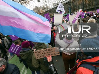 Demonstrators hold placards and a transgender flag as they participate in a protest to condemn violence against women, called by feminist or...