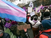 Demonstrators hold placards and a transgender flag as they participate in a protest to condemn violence against women, called by feminist or...