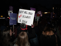 A demonstrator holds a placard reading ''not all men, but always a man'' during a protest to condemn violence against women, called by femin...