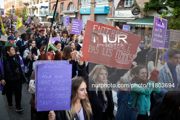 A woman holds a red placard reading 'Bury violence not women'. Women from the collective NousToutes and other organizations such as SUD or A...