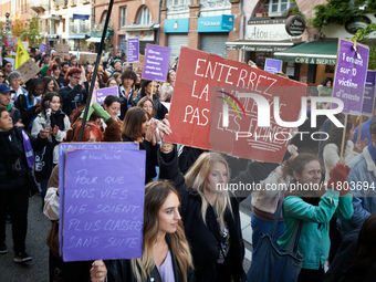 A woman holds a red placard reading 'Bury violence not women'. Women from the collective NousToutes and other organizations such as SUD or A...