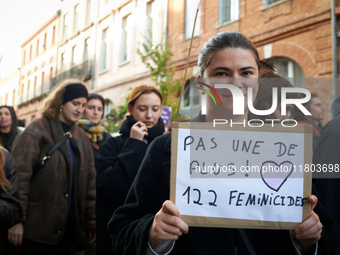 A young woman holds a cardboard sign reading 'Not one more! 122 feminicides'. Women from the collective NousToutes and other organizations s...