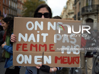 A woman holds a placard reading 'One isn't born a woman but one will die from it'. Women from the collective NousToutes and other organizati...