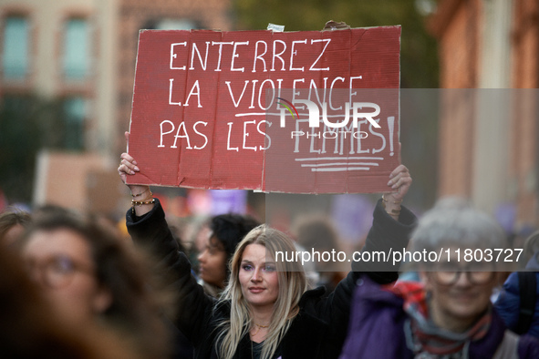 A woman holds a placard reading 'Bury violence not women'. Women from the collective NousToutes and other organizations such as SUD or Amnes...