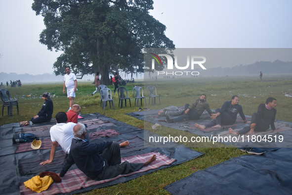 People perform yoga inside a ground on a foggy winter morning in Kolkata, India, on November 24, 2024. 