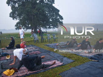 People perform yoga inside a ground on a foggy winter morning in Kolkata, India, on November 24, 2024. (