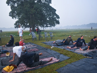 People perform yoga inside a ground on a foggy winter morning in Kolkata, India, on November 24, 2024. (