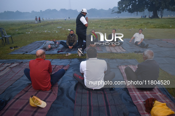 People perform yoga inside a ground on a foggy winter morning in Kolkata, India, on November 24, 2024. 