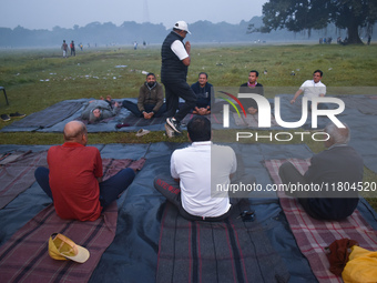 People perform yoga inside a ground on a foggy winter morning in Kolkata, India, on November 24, 2024. (