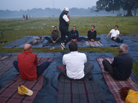 People perform yoga inside a ground on a foggy winter morning in Kolkata, India, on November 24, 2024. (