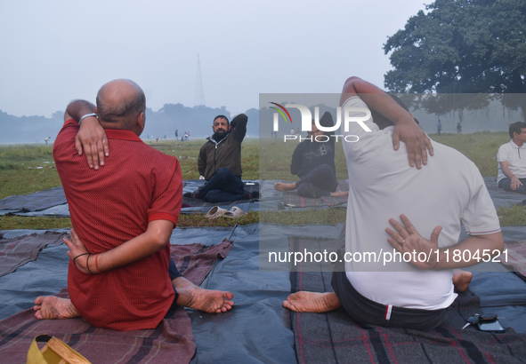 People perform yoga inside a ground on a foggy winter morning in Kolkata, India, on November 24, 2024. 