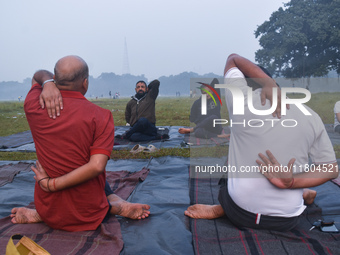 People perform yoga inside a ground on a foggy winter morning in Kolkata, India, on November 24, 2024. (