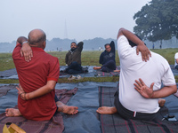 People perform yoga inside a ground on a foggy winter morning in Kolkata, India, on November 24, 2024. (