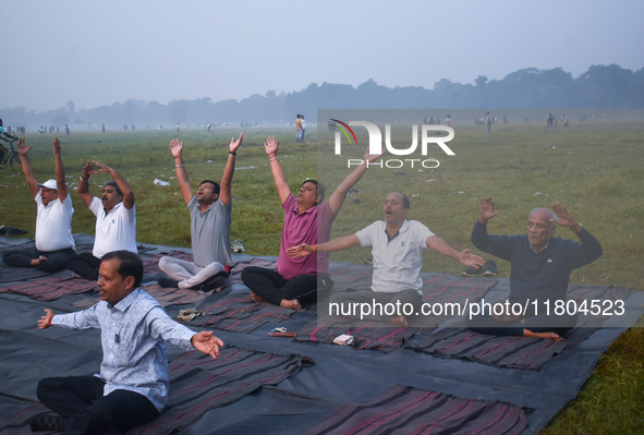 People perform yoga inside a ground on a foggy winter morning in Kolkata, India, on November 24, 2024. 