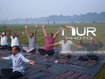 People perform yoga inside a ground on a foggy winter morning in Kolkata, India, on November 24, 2024. (