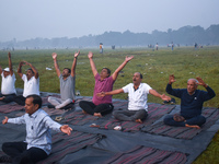 People perform yoga inside a ground on a foggy winter morning in Kolkata, India, on November 24, 2024. (