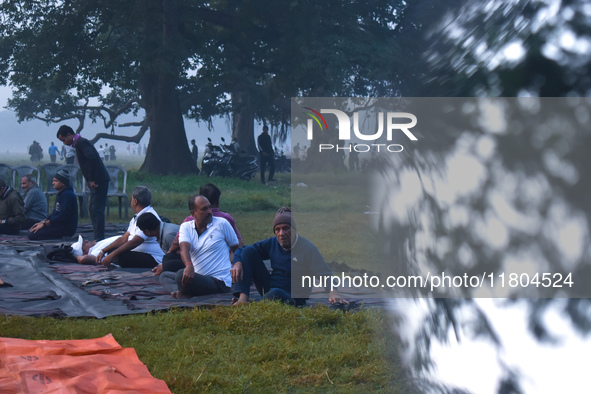 People perform yoga inside a ground on a foggy winter morning in Kolkata, India, on November 24, 2024. 