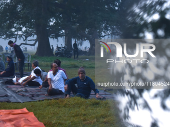 People perform yoga inside a ground on a foggy winter morning in Kolkata, India, on November 24, 2024. (