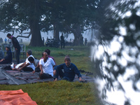 People perform yoga inside a ground on a foggy winter morning in Kolkata, India, on November 24, 2024. (