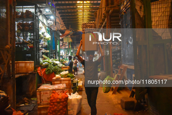 A boy carries eggs on his head while walking inside a wholesale market in Kolkata, India, on November 24, 2024. 