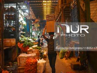 A boy carries eggs on his head while walking inside a wholesale market in Kolkata, India, on November 24, 2024. (