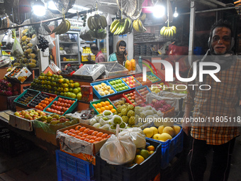 A person passes next to a fruit shop inside a wholesale market in Kolkata, India, on November 24, 2024. (