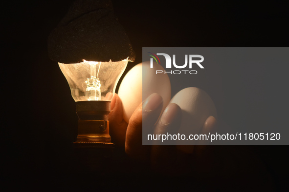 A vendor checks eggs against the light while selling eggs inside a wholesale market in Kolkata, India, on November 24, 2024. 