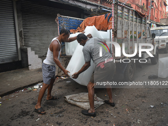 Labourers unload a large ice block from a truck inside a wholesale market in Kolkata, India, on November 24, 2024. (