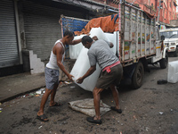 Labourers unload a large ice block from a truck inside a wholesale market in Kolkata, India, on November 24, 2024. (