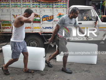 Labourers unload a large ice block from a truck inside a wholesale market in Kolkata, India, on November 24, 2024. (