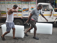 Labourers unload a large ice block from a truck inside a wholesale market in Kolkata, India, on November 24, 2024. (