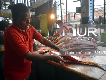 A vendor prepares fish inside a wholesale market in Kolkata, India, on November 24, 2024. (