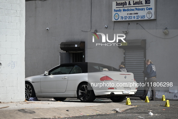 Evidence markers highlight where shell casings and other evidence are discovered by a white vehicle where a 35-year-old man is killed after...