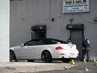 Evidence markers highlight where shell casings and other evidence are discovered by a white vehicle where a 35-year-old man is killed after...