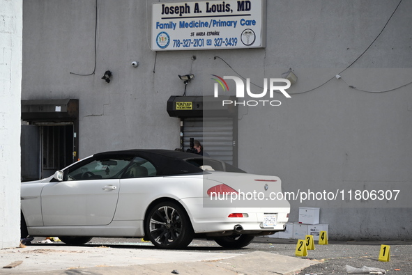 Evidence markers highlight where shell casings and other evidence are discovered by a white vehicle where a 35-year-old man is killed after...