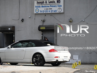 Evidence markers highlight where shell casings and other evidence are discovered by a white vehicle where a 35-year-old man is killed after...