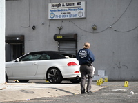 Evidence markers highlight where shell casings and other evidence are discovered by a white vehicle where a 35-year-old man is killed after...