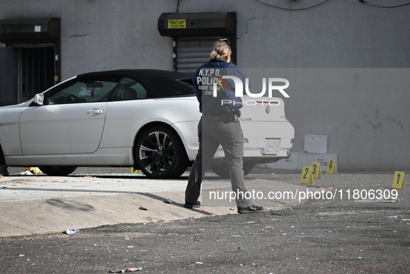 Evidence markers highlight where shell casings and other evidence are discovered by a white vehicle where a 35-year-old man is killed after...