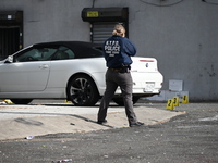 Evidence markers highlight where shell casings and other evidence are discovered by a white vehicle where a 35-year-old man is killed after...